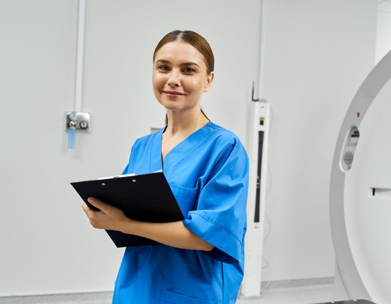 Female doctor in blue scrubs stands confidently in the diagnostics area